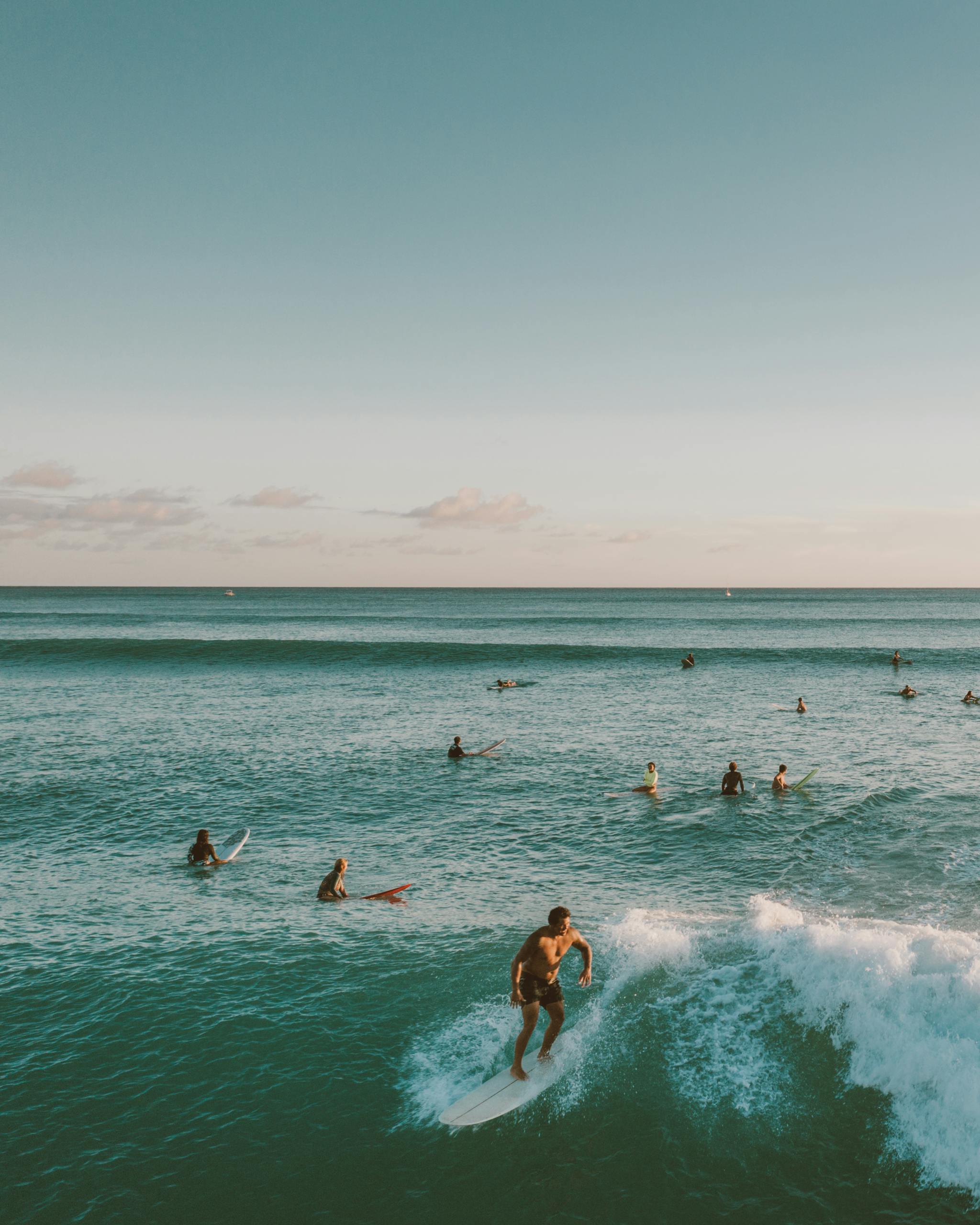 A vibrant scene of surfers catching waves in Hawaii's blue ocean under clear skies.