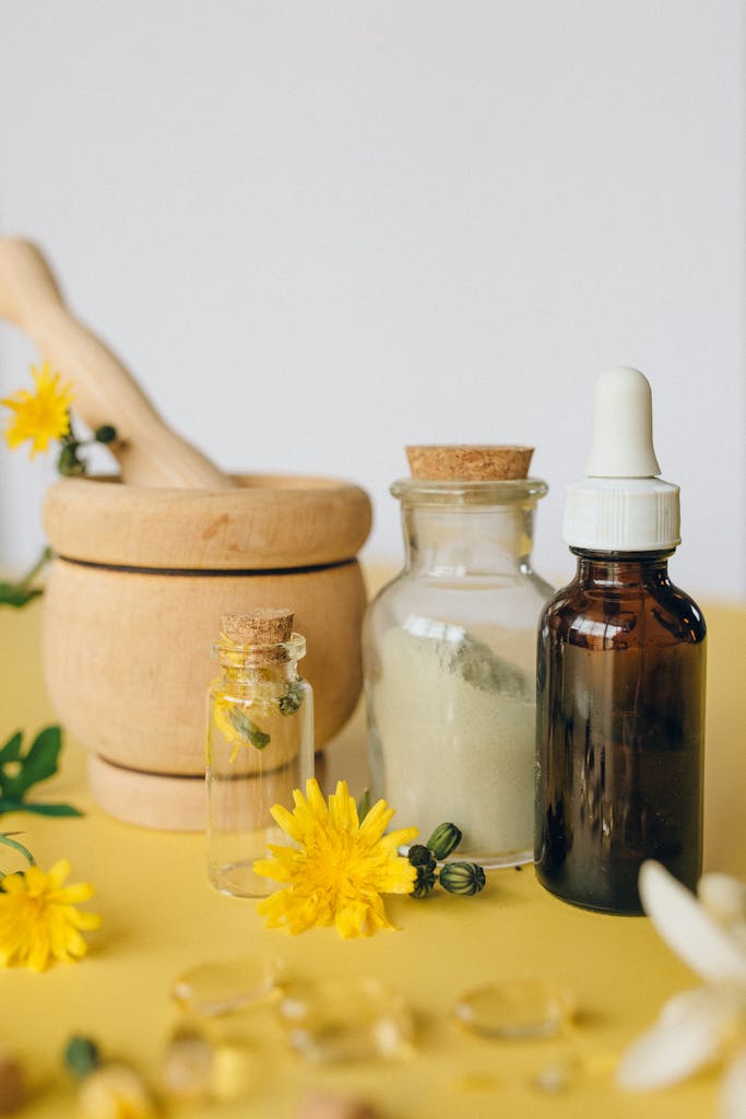 A still life of herbal medicine tools including mortar, dropper, and vials with flowers.