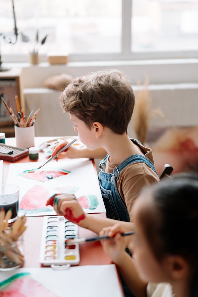 Children painting with watercolors in a sunny, indoor art workshop.