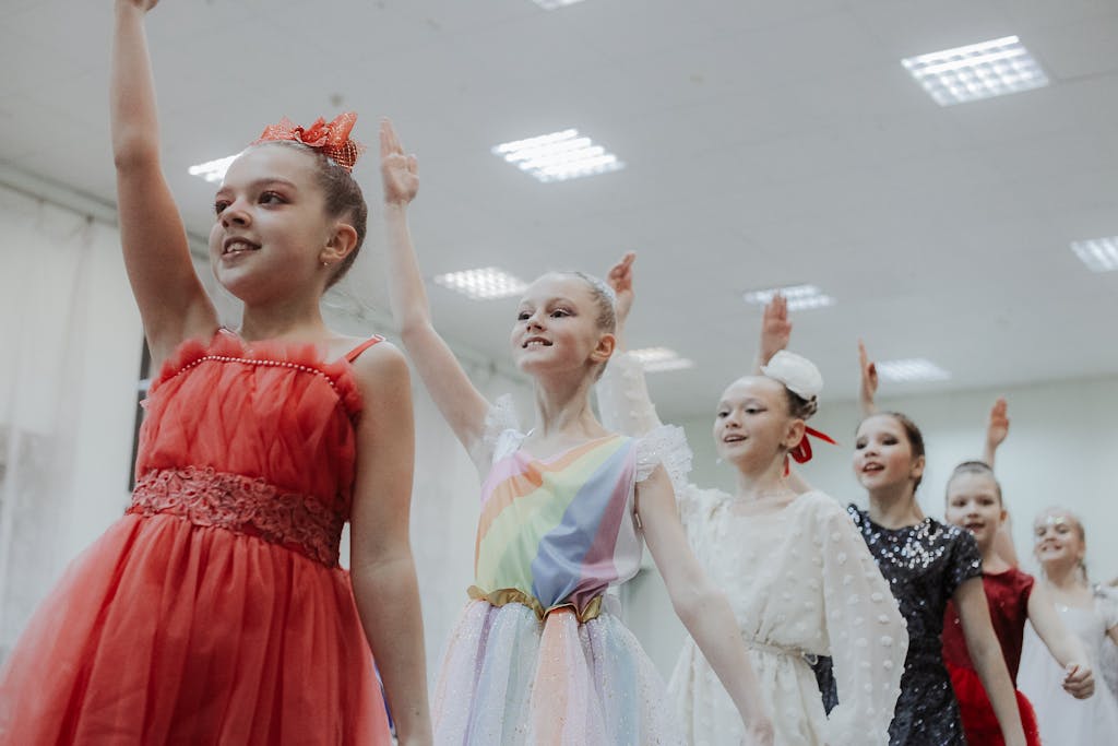 Group of young ballet dancers spinning with grace in vibrant costumes indoors.
